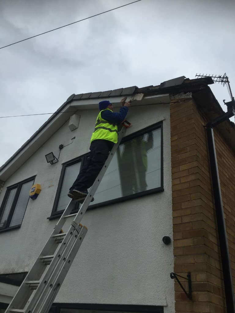 Roofer on ladder fitting fascia at roof edge in Hyndburn by Holgates Roofing