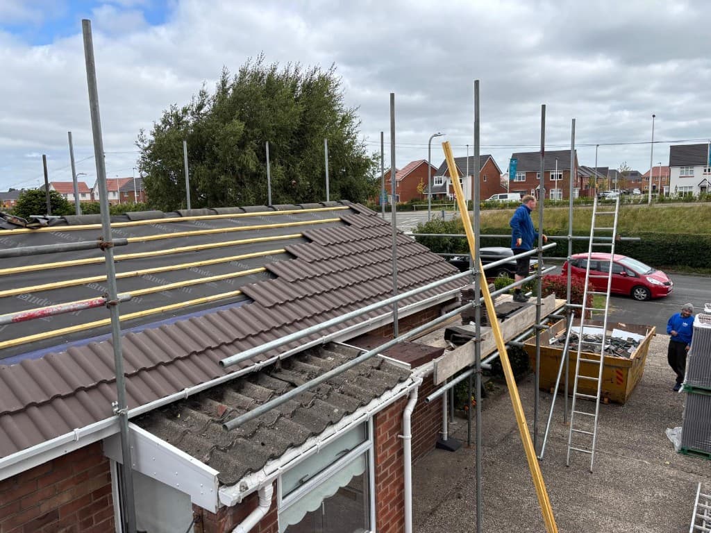Roofer fitting gutter on pebbledash house in Hyndburn by Holgates Roofing